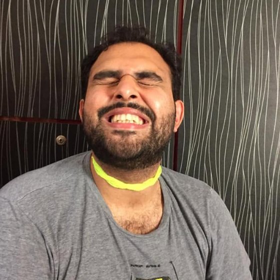 Muhammad Waqar J Khan, laughing, a neon net collar at his throat