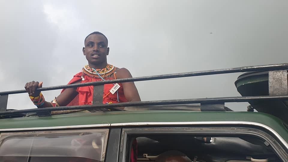 red beadwork, one arm on the jeep, the dust coming.