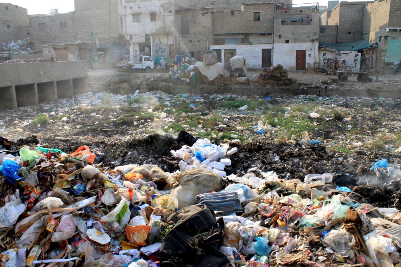 a lot full of garbage, houses right up to the edge of it.