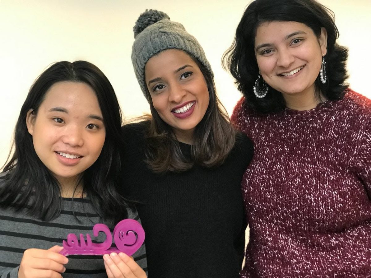 Three of the CUE team in Berlin, 2017, holding the magenta laser-cut cue sign
