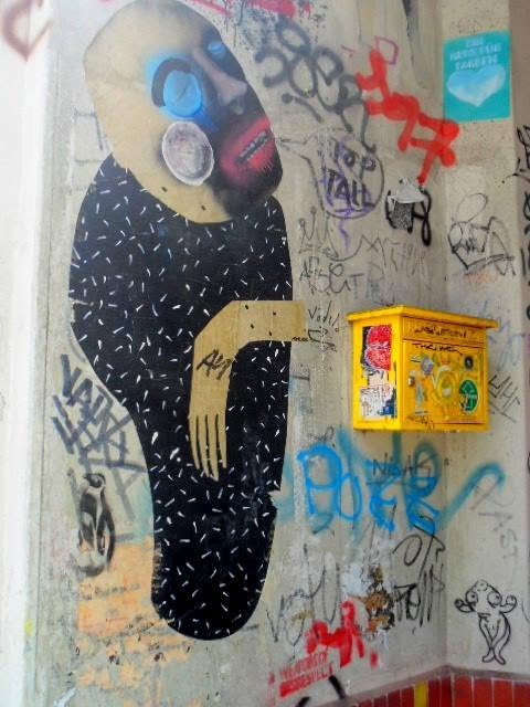 a pasted-up body with no bones &mdash; black, speckled, one wooden arm, a face made up like a mourner&rsquo;s. glued on wet and buried under other people&rsquo;s names inside a week. every wall here is a lease, not a deed.