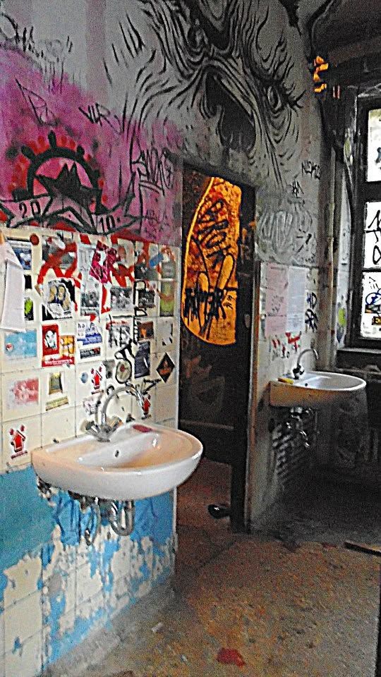 the toilets. two sinks, no doors, a monster inked across the ceiling and a decade of flyers tiled over the tiles. this is what people mean when they say a building was free   nobody was coming to fix it, so everybody was allowed to change it.