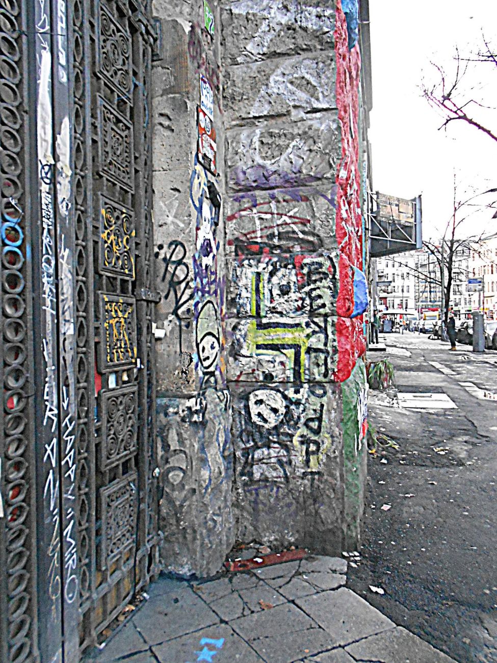 a corner in january   the ironwork tagged, the render gone, four artists deep on one pillar, the street empty behind. this is the texture nobody photographs: not a mural, just a wall that everyone has touched.