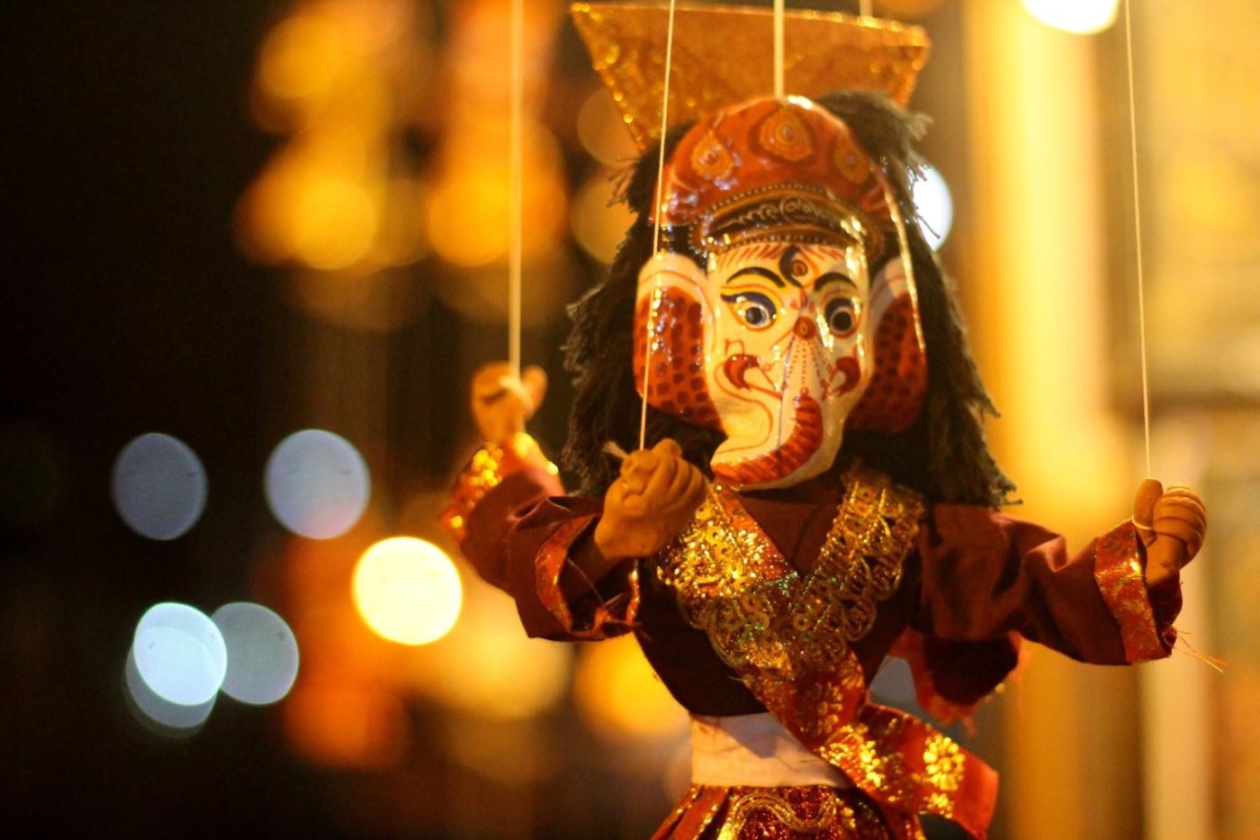 ganesh on strings, in a night market, out of focus behind him.