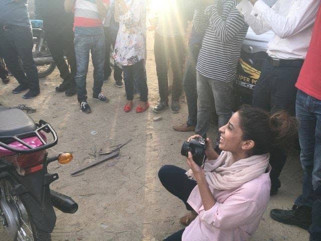Saba crouching with a camera in a crowd