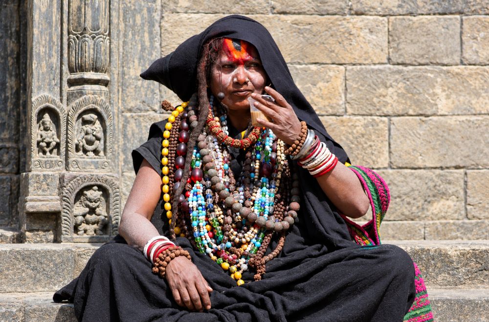 A sadhvi in black, dozens of bead malas, drinking chai