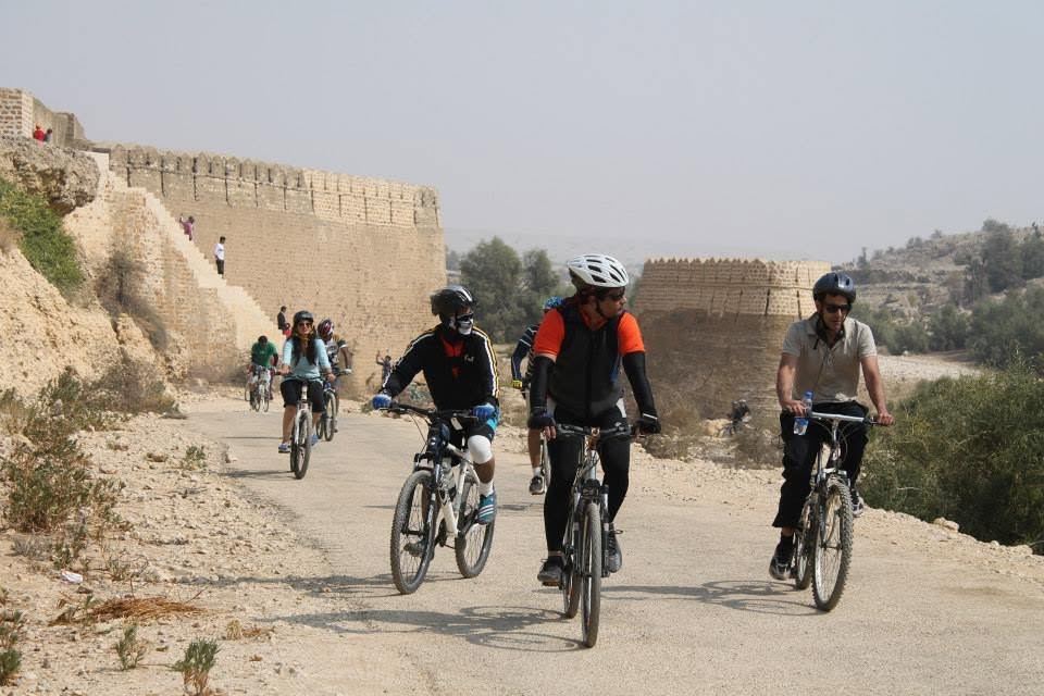 the rally rides past the fort wall. helmets, gears, an old fort watching.