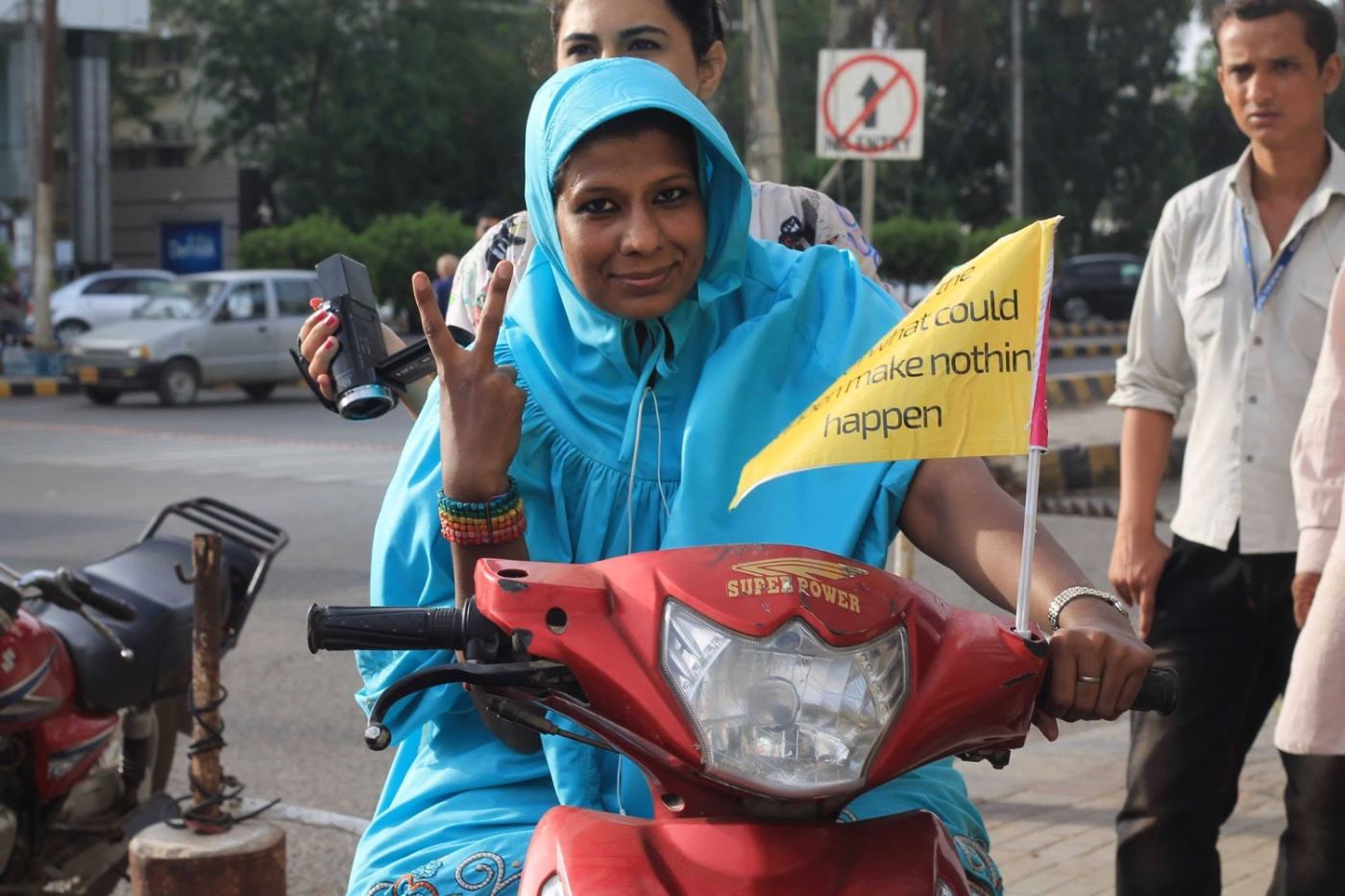 a red scooter, a flag, and a woman riding through traffic that wasn’t expecting her.