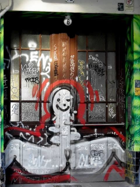 a doorway painted shut — a red halo round a face, tags over tags over tags.