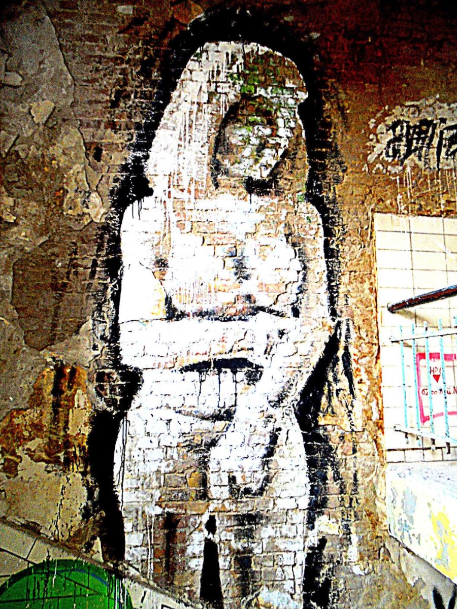 a figure in white, dripping, painted straight onto raw brick. nobody signed it.