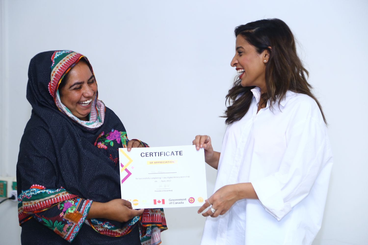 Saba handing a digital literacy certificate to a laughing champion
