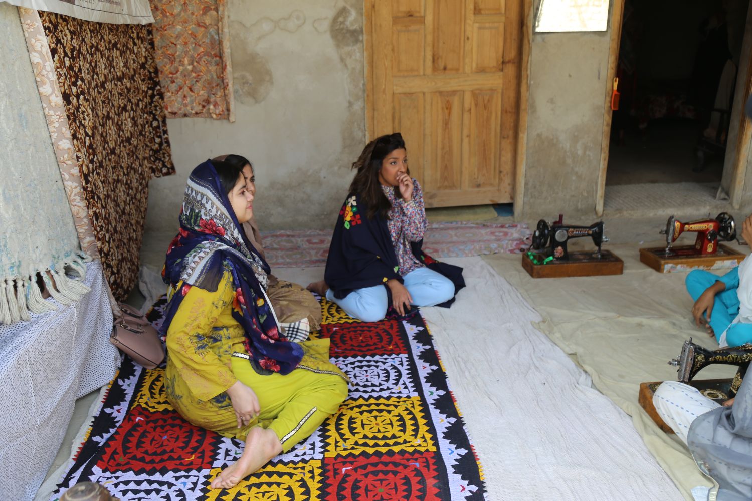 Two women sitting on the floor of a village room during a listening party