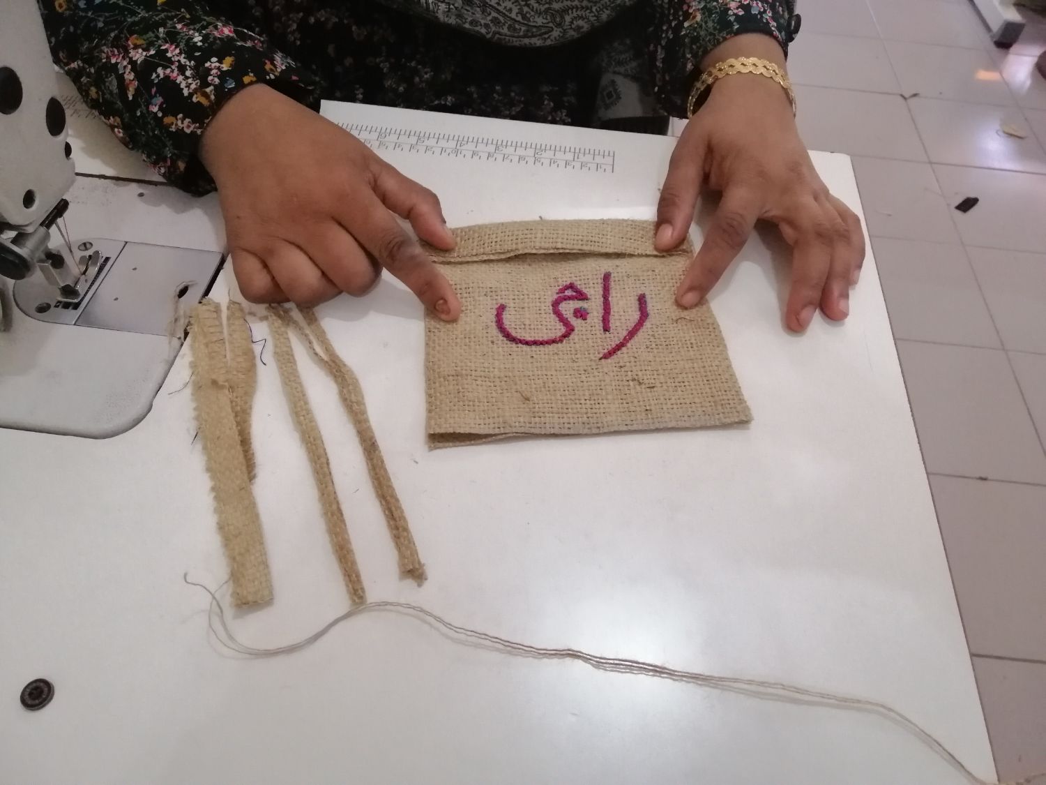 Hands measuring jute cloth beside a Juki machine