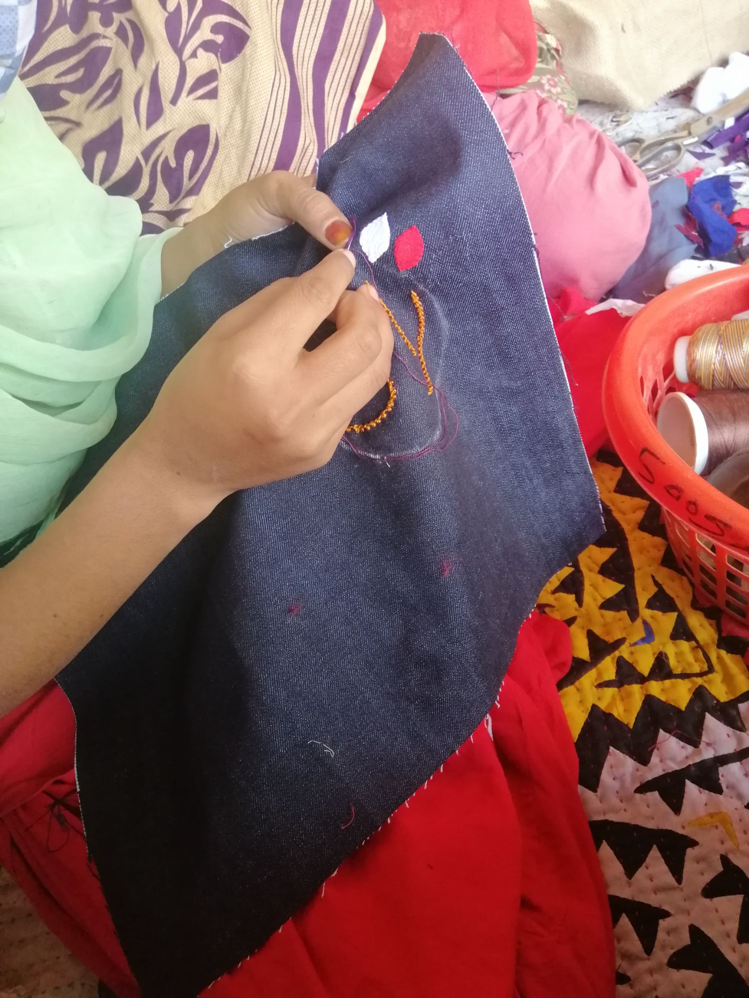 A girl embroiding a navy Raaji pouch by hand
