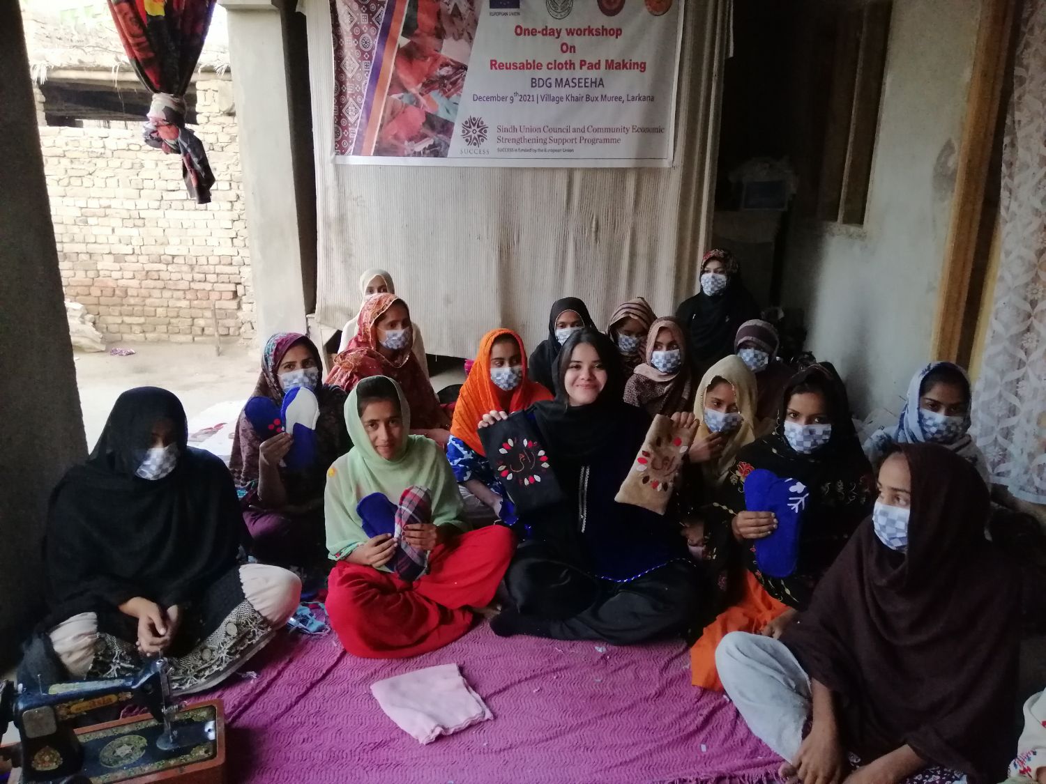Seventeen women holding up finished pads and Raaji pouches