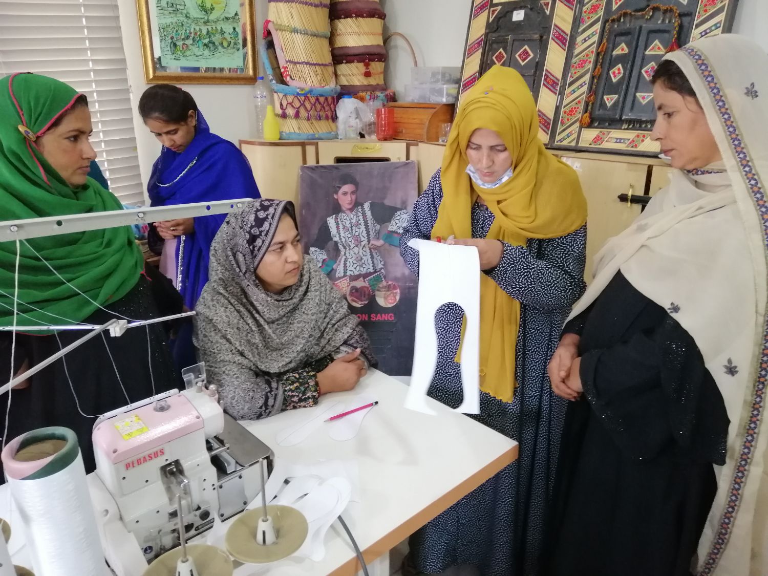Meera holds up a paper pad template to a group of women
