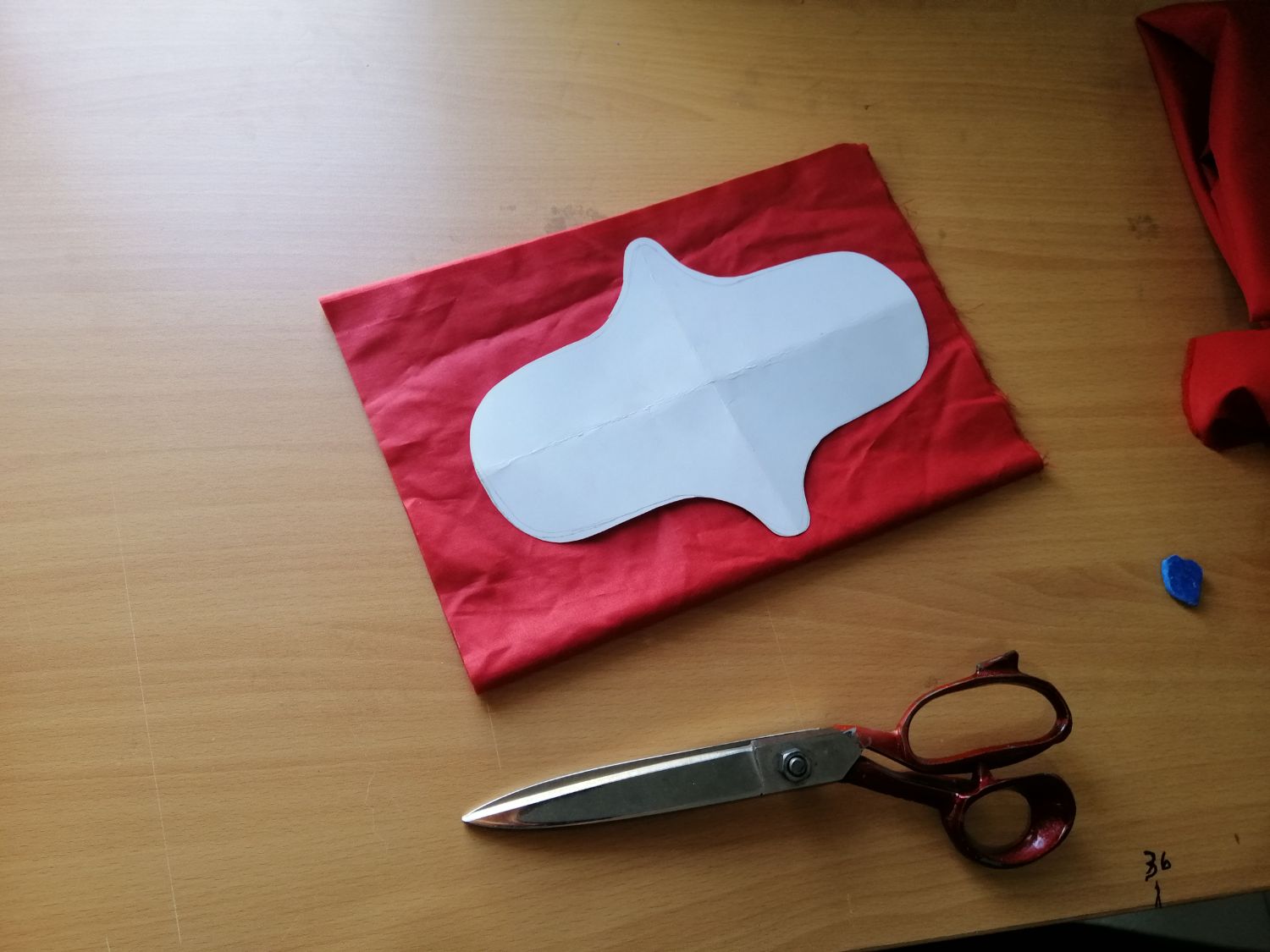 A paper template on red cloth beside a pair of shears