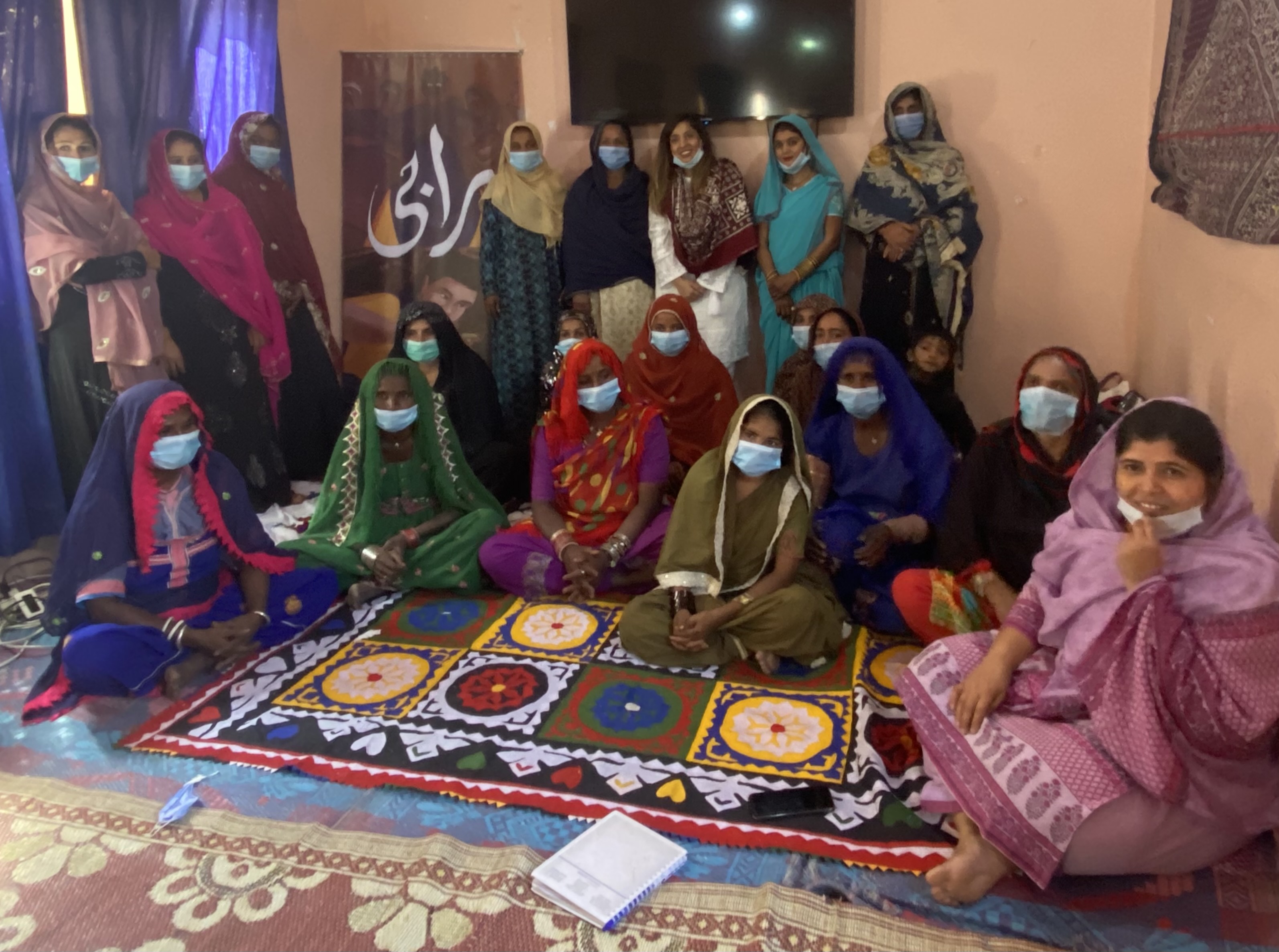A group of women standing in front of a Raaji banner at NRSP Tando Allahyar