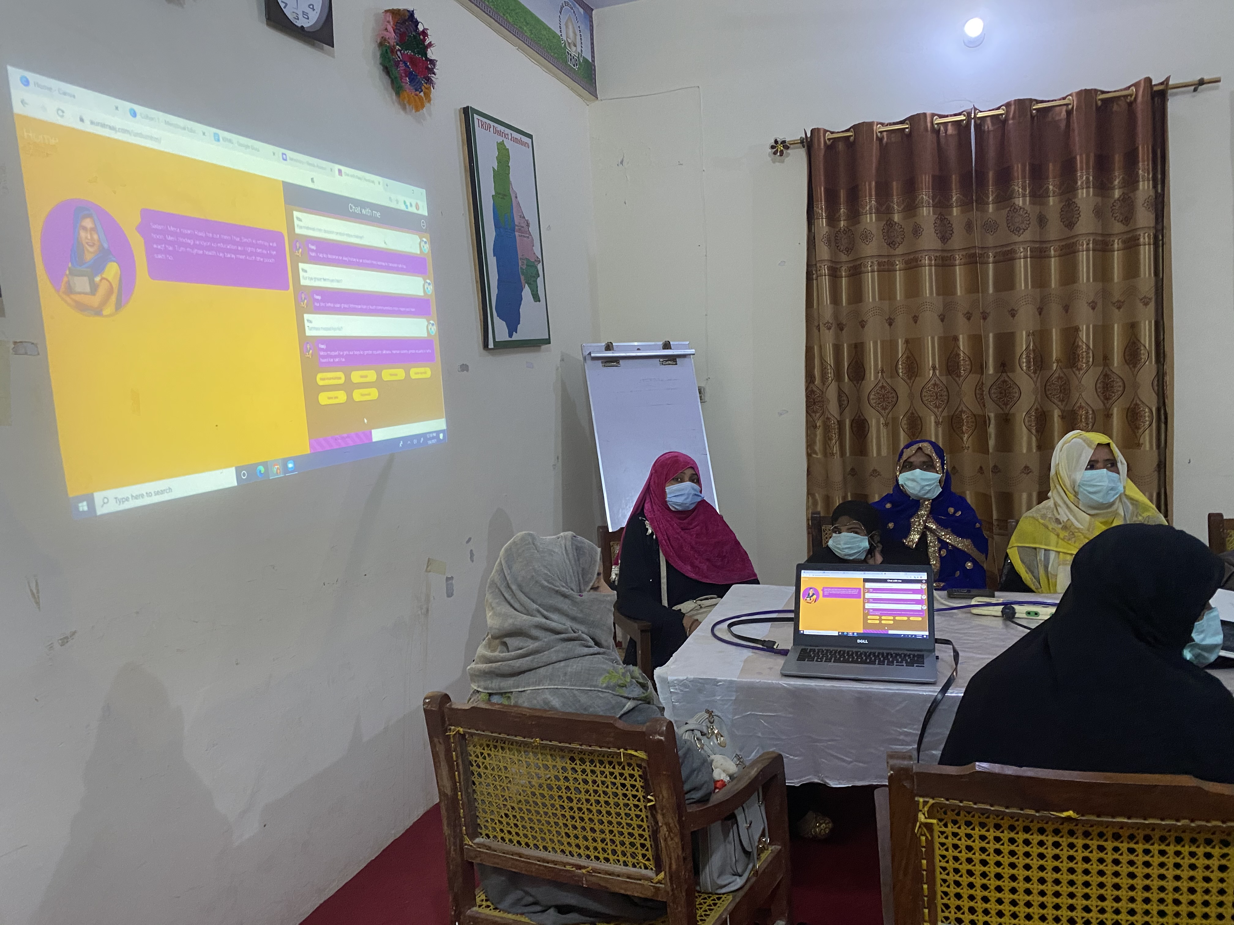 Raaji projected on a wall beside a laptop at TRDP Jamshoro