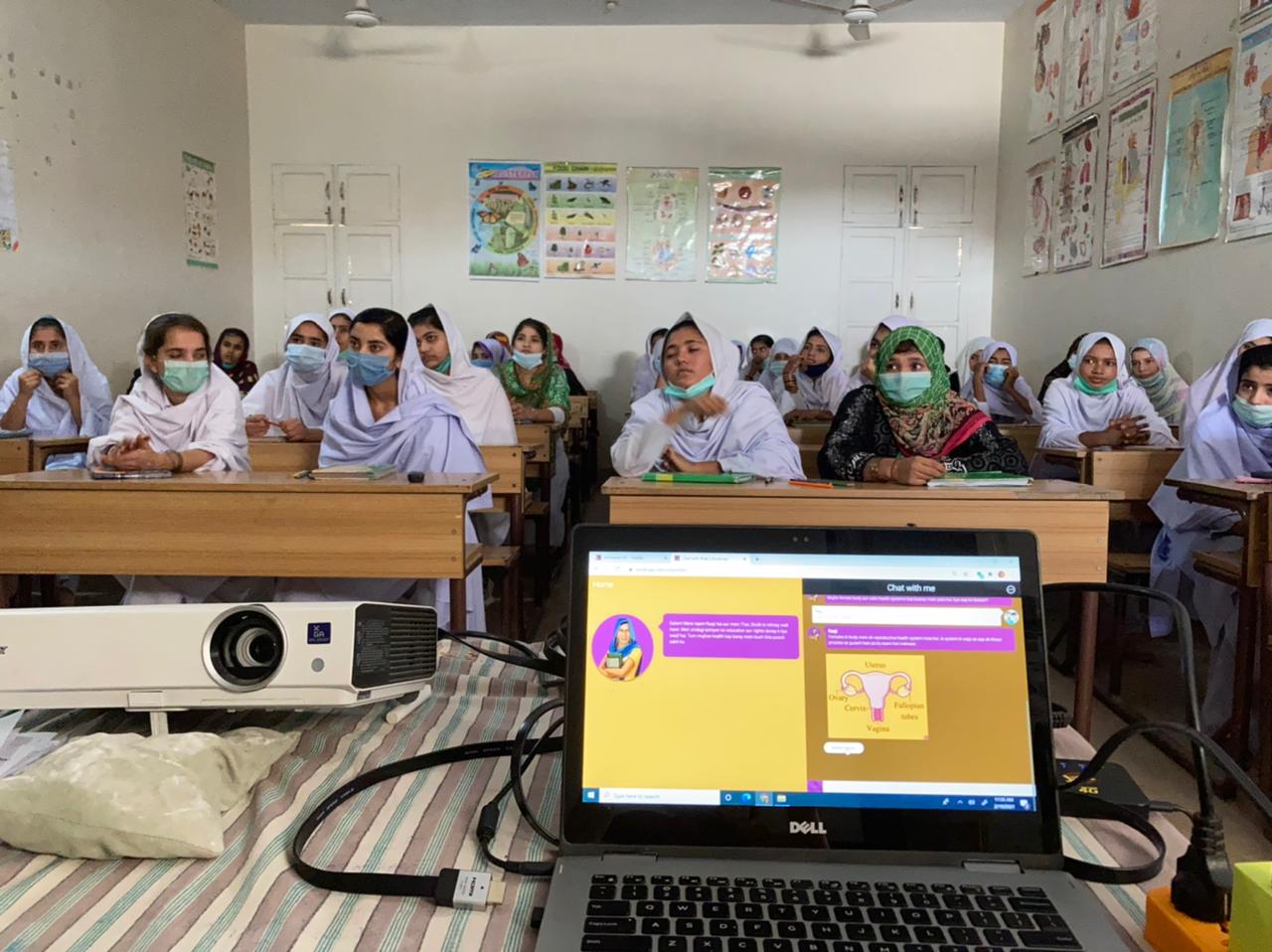 A classroom of girls watching Raaji on a projector