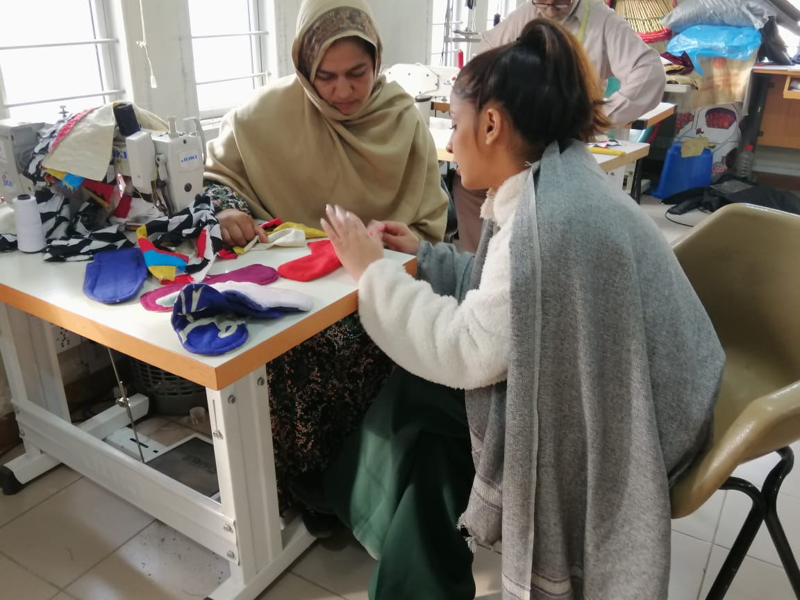 Two women working a pad prototype at an industrial sewing table
