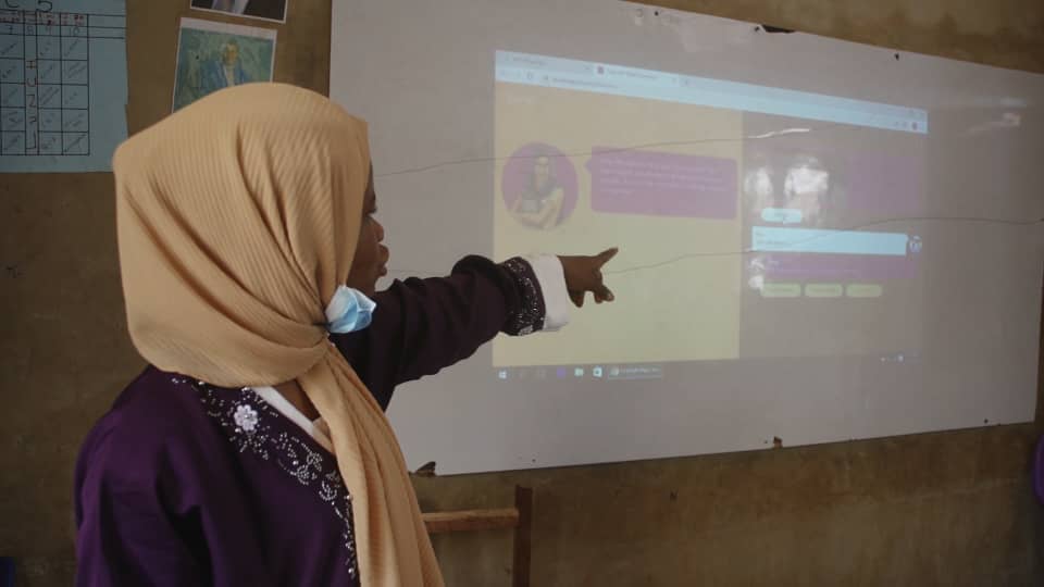 A woman pointing at Raaji projected on a wall
