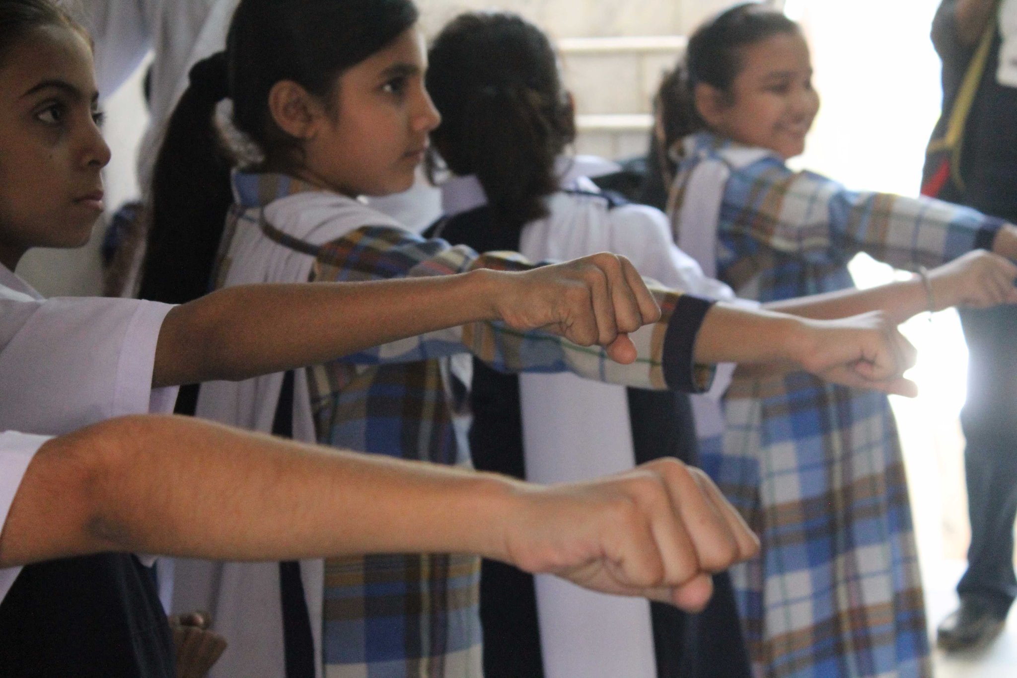 Schoolgirls practising a punch in unison, fists in foreground