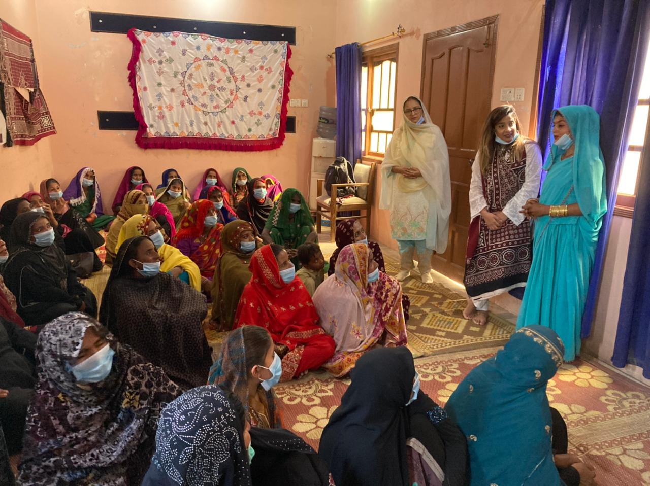 Saba standing with two women talking to a seated room